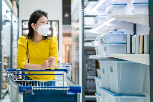 New normal lifestyle asian female yellow dress wear protecting mask shopping in department store after end of lockdown quarantine period