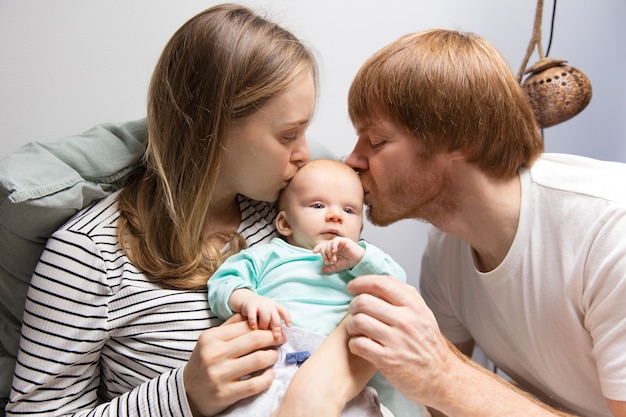 New parents kissing red haired baby head