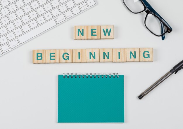 New start and business concept with wooden blocks, glasses, keyboard, pen, notebook on white background flat lay.