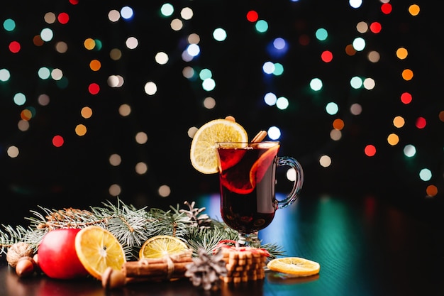 New Year and Christmas decor. Glasses with mulled wine stand on table with oranges, apples