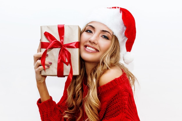 새해 또는 크리스마스 이브 분위기. 선물 상자를 들고 가장 무도회 모자에 금발 매력적인 여자 즐거운 분위기입니다.