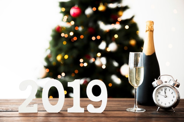 Новогодняя композиция с бутылкой шампанского и часами на столе