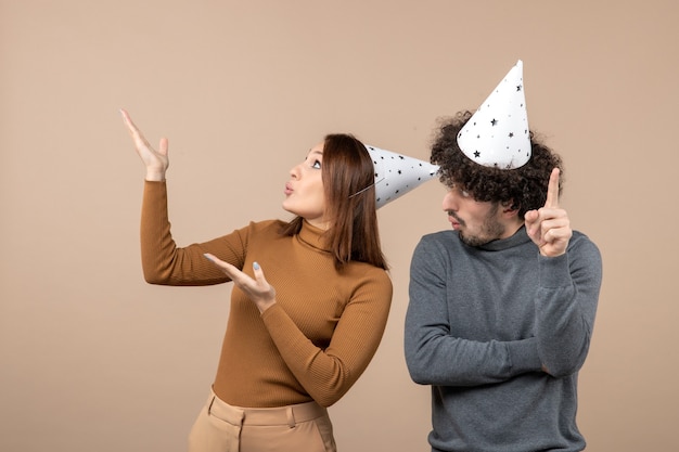 New year concept with lovely excited happy young couple wear new year hat girl looking above