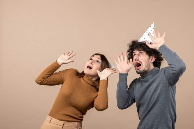 New year concept with lovely excited happy young couple wear new year hat looking above girl