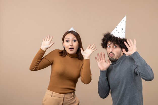 New year concept with shocked young couple wear new year hat girl and guy on gray