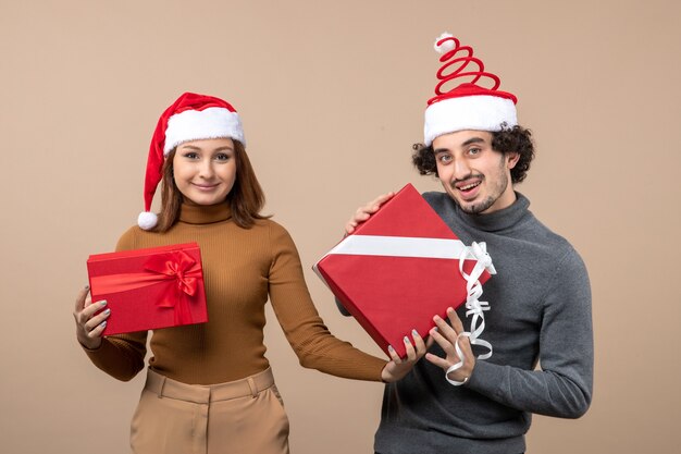 New year mood festive concept with cool lovely couple wearing red santa claus hats on gray