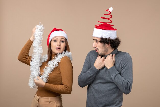 New year mood festive concept with excited cool satisfied lovely couple wearing red santa claus hats on gray footage