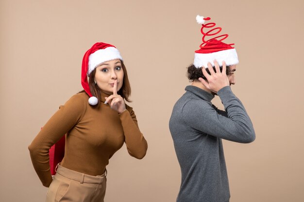 New year mood festive concept with funny lovely couple wearing red santa claus hats girl making surprise