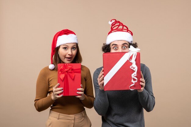 New year mood and party concept - young energetic excited lovely couple holding gifts wearing santa claus hats