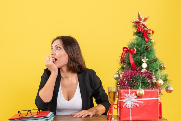 New year mood with beautiful business lady looking at something suprisingly and sitting at a table in the office