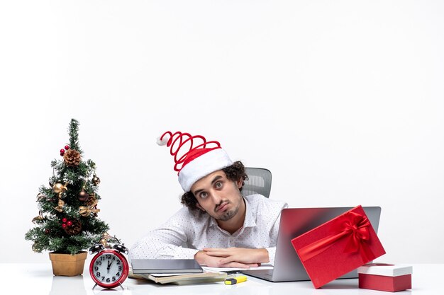 New year mood with confused young businessman with funny santa claus hat feeling surprised in the office on white background
