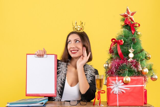 New year mood with dreamy charming lady in suit with crown holding document in the office 