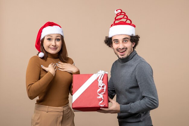 Новогоднее настроение с забавной счастливой прекрасной парой в красных шапках санта-клауса на сером