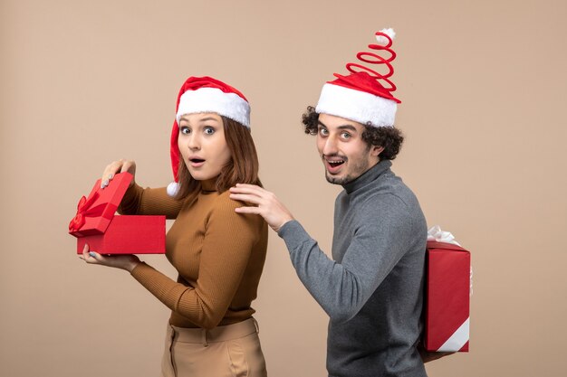 New year mood with funny lovely couple wearing red santa claus hats on gray