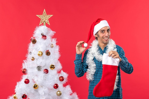 New year mood with young man with santa claus hat holding christmas sock and decoration