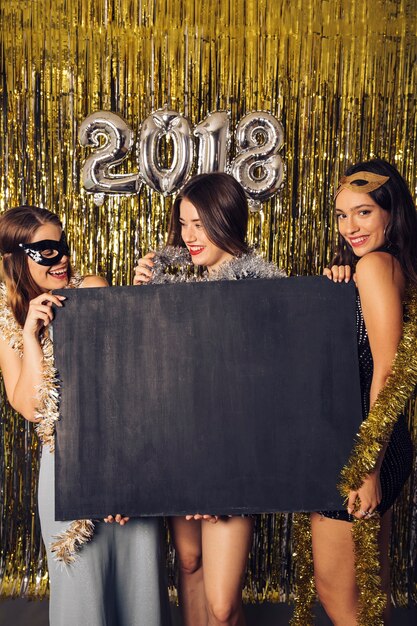 女の子と新年パーティーの概念は、黒板を持って