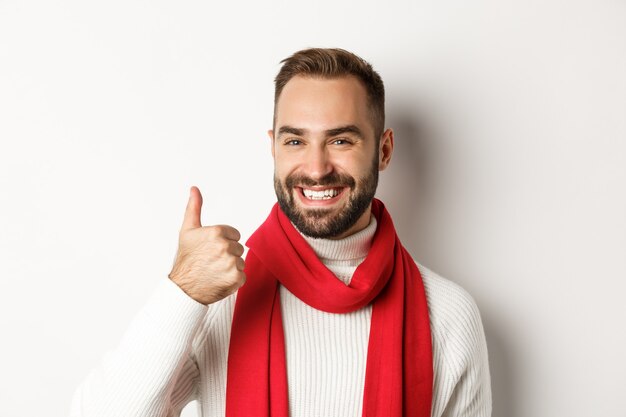 New Year party and winter holidays concept. Close-up of handsome satisfied man showing thumb up, wishing happy Christmas, standing over white background.