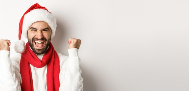 Foto gratuita primo piano di concetto di festa di capodanno e vacanze invernali di uomo eccitato in cappello di babbo natale che si rallegra vincendo o