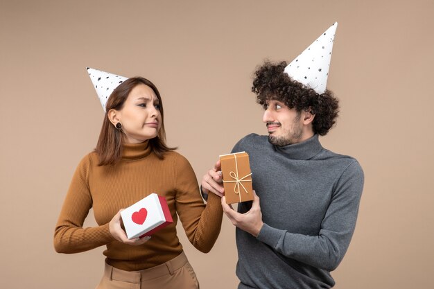 若いカップルがお互いを見つめながら新年の撮影は、心のある新年の帽子の酸っぱい顔の女の子を着用します