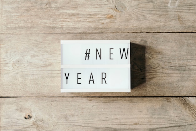 Free photo new year text in led panel with wooden background