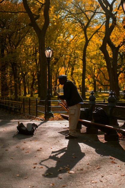 New York City Manhattan Central Park in the fall. A street musician plays saxophone in Central Park in New York City.