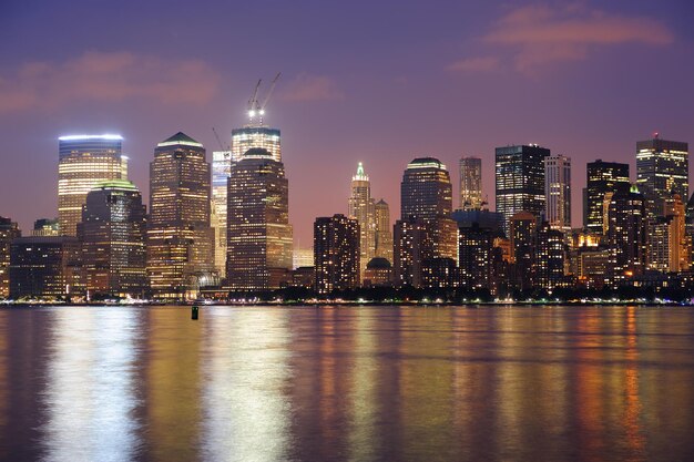 New York City Manhattan downtown skyline at dusk with skyscrapers illuminated over Hudson River panorama