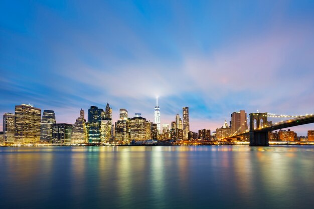 New York City Manhattan midtown at dusk with skyscrapers illuminated over east river