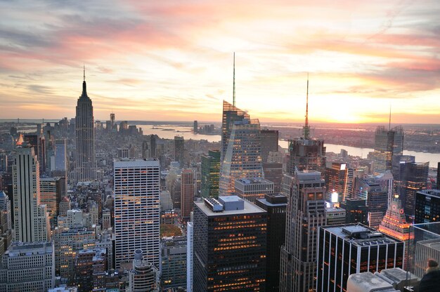 マンハッタンのミッドタウンのカラフルな雲と高層ビルと日没時のニューヨーク市のスカイラインの空中写真。