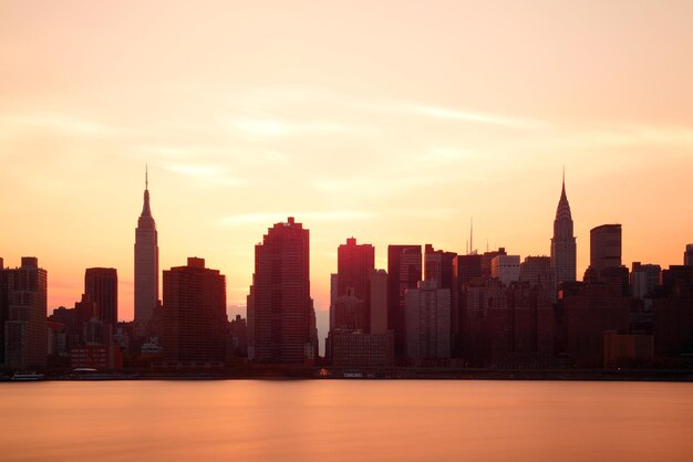 ニューヨーク市の高層ビルは日の出の都会の景色をシルエットします。