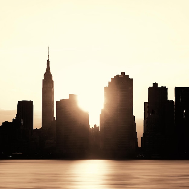 뉴욕시 고층 빌딩은 일출 시 도시 전망을 실루엣으로 표시합니다.
