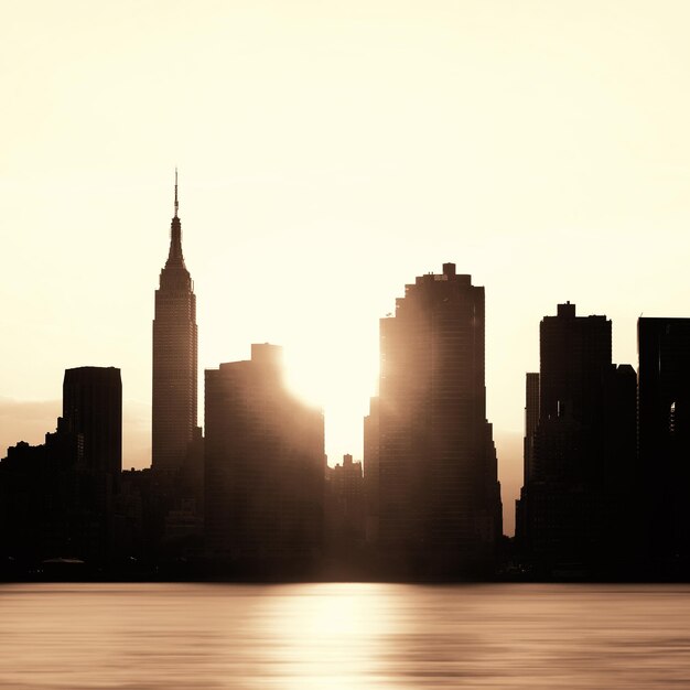 뉴욕시 고층 빌딩은 일출 시 도시 전망을 실루엣으로 표시합니다.