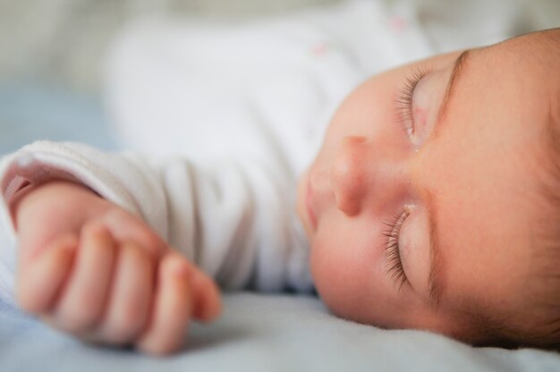 Newborn baby girl sleeping on blue sheets at home