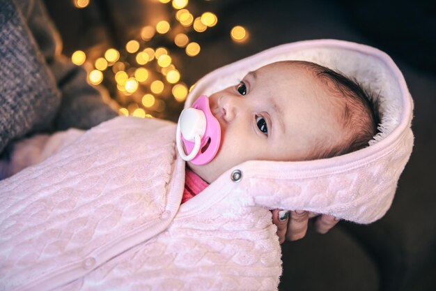 Newborn baby girl with pacifier on blurred background with bokeh