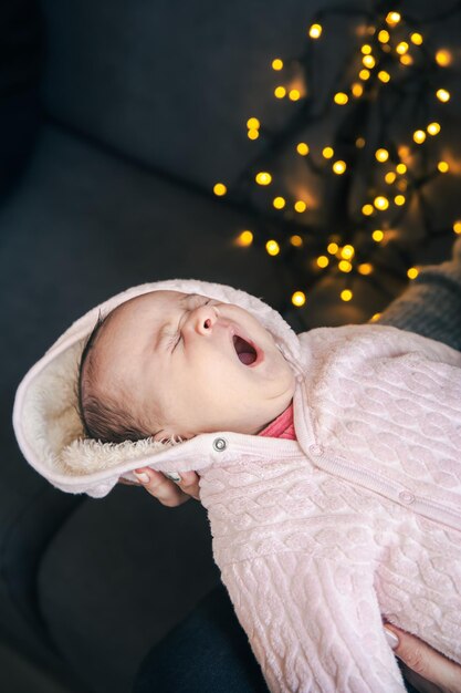 Newborn baby girl yawns on blurred background with bokeh