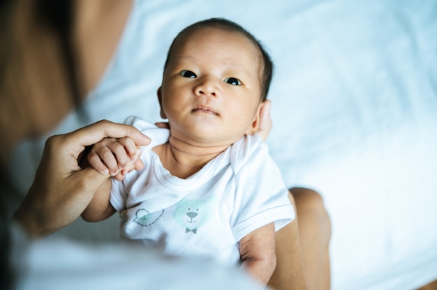 Newborn baby holding hands mom