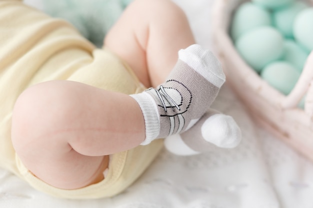 Newborn baby legs in socks on easter eggs background. 