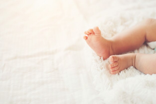 하얀 침대에 신생아 아기 다리입니다.