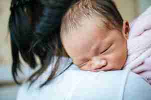 Free photo newborn baby sleeping on the mother's shoulder