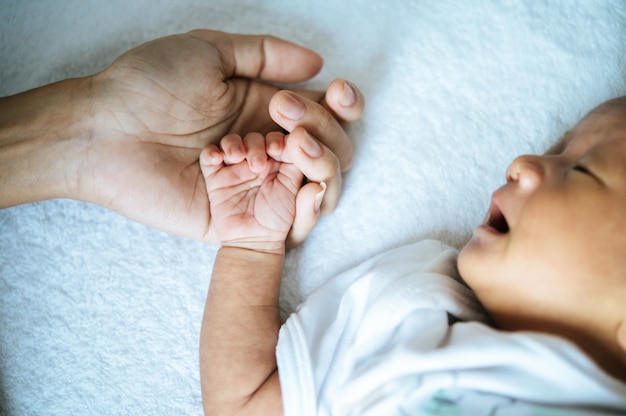 newborn baby sleeping and puts the hand on the mother's hand