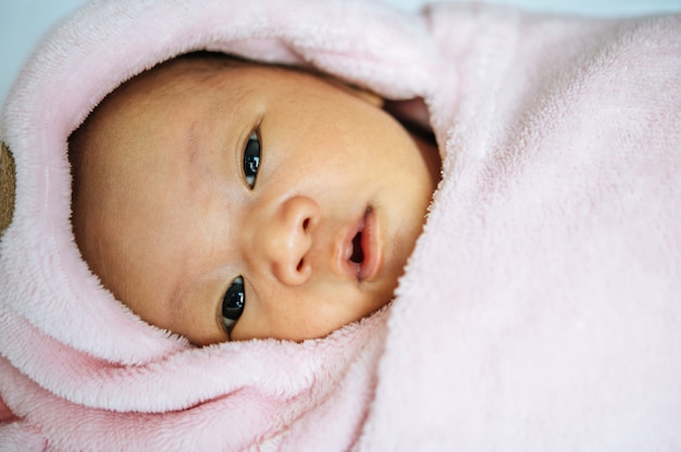 生まれたばかりの赤ちゃんは毛布の上で寝て目を開く