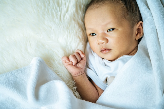 生まれたばかりの赤ちゃんは毛布の上で寝て目を開く