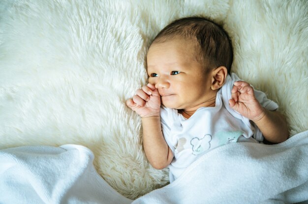 newborn baby sleeps on the blanket and opens the eyes