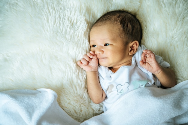 новорожденный ребенок спит на одеяле и открывает глаза