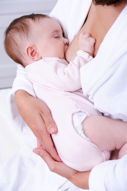 Новорожденный ребенок сосет материнское молоко