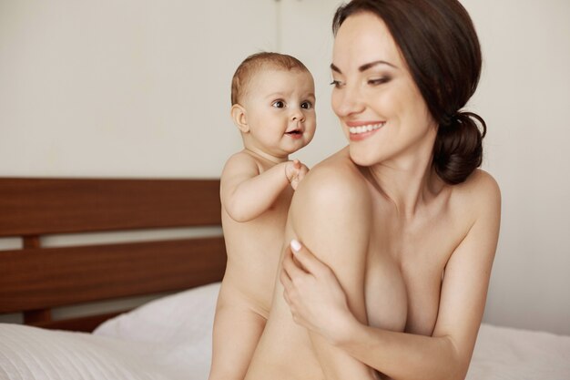 Newborn baby touching her mom standing maternity at its best