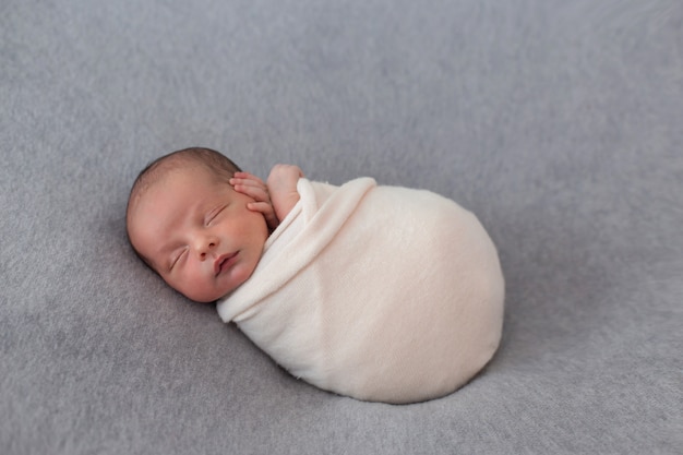 Newborn baby wrapped with soft pink tissue.