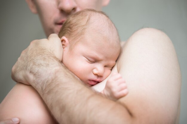 Newborn child sleeping in male arms