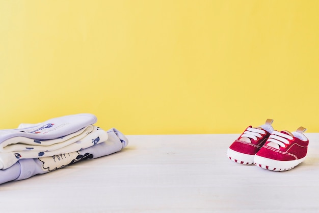 Newborn concept with baby shoes and pile of clothes