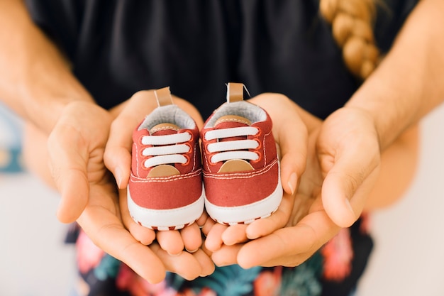 Концепция новорожденного с парой, держащей обувь в руках