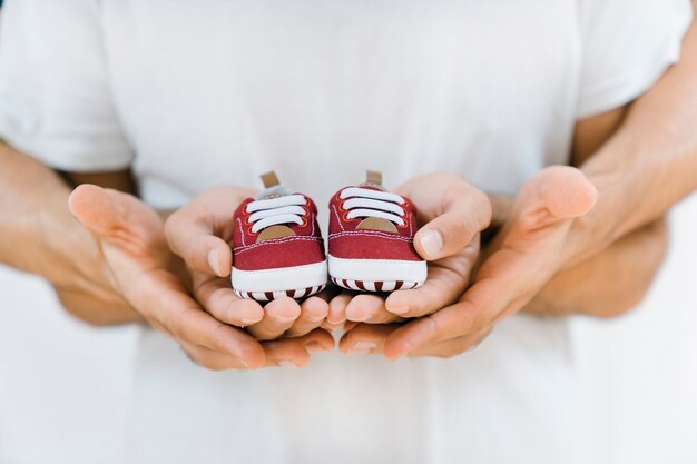 Newborn concept with gay couple holding shoes